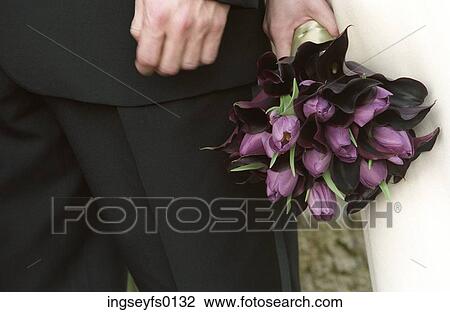 Stock Image - Hands Of Caucasian Bride And Groom Standing With Bouquet. Fotosearch