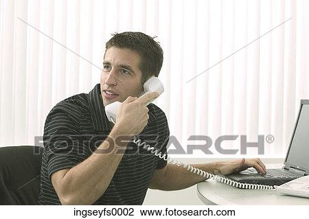 Stock Image - Man on Phone with Laptop. Fotosearch