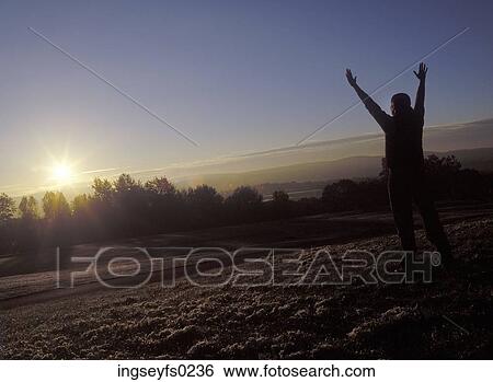Stock Photograph - Person Greeting Sunrise With Arms Raised. Fotosearch