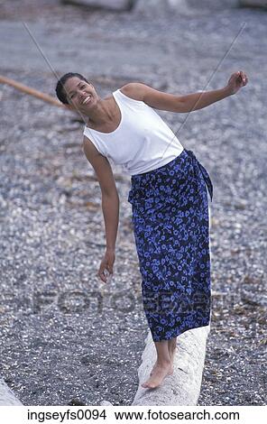 Smiling African American Woman Standing On A Log On A Rocky Beach View Large Photo Image Picture - Smiling African American Woman Standing On A Log On A Rocky Beach. Fotosearch