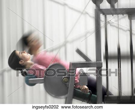Stock Image - Woman Working Out On Exercise Machine. Fotosearch
