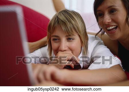 Stock Image - Close-up of a two young women looking at a laptop and smiling. Fotosearch