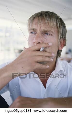 Stock Image - Close-up of a young man smoking a cigarette. Fotosearch