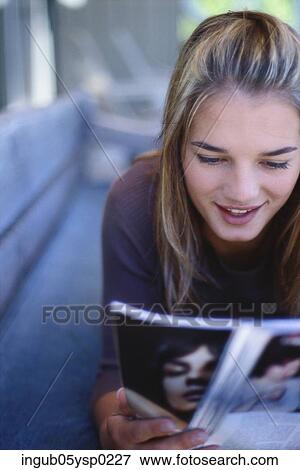Close-up of a young woman lying and reading a magazine View Large Photo Image Stock Photo - Close-up of a young woman lying and reading a magazine. Fotosearch