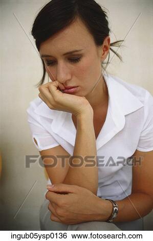 Stock Photograph - Close-up of a young woman sitting with her chin in her hand. Fotosearch