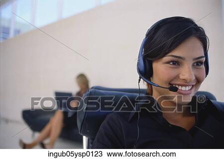 Stock Image - Close-up of a young woman wearing a headset and smiling. Fotosearch