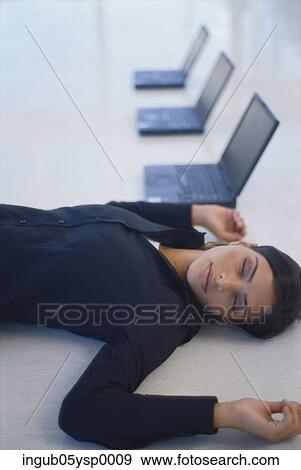 Stock Photo - High angle view of a businesswoman lying beside a row of laptops. Fotosearch