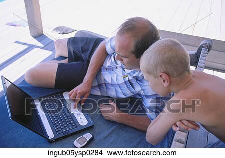 High angle view of a mid adult man working on a laptop with his son View Large Photo Image Picture - High angle view of a mid adult man working on a laptop with his son. Fotosearch