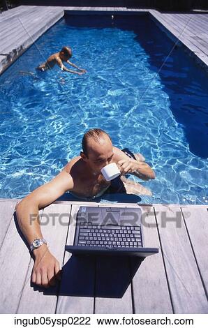 High angle view of a young man in a swimming pool with a laptop on the ledge View Large Photo Image Stock Image - High angle view of a young man in a swimming pool with a laptop on the ledge. Fotosearch