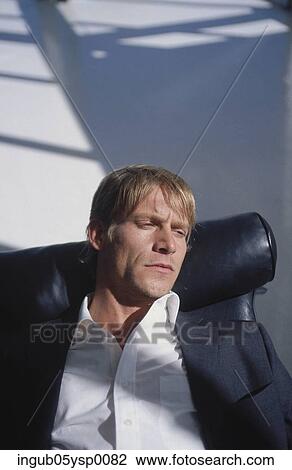 Stock Image - High angle view of a young man lying on a chair. Fotosearch