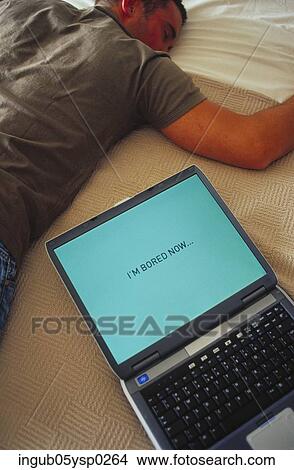 Picture - High angle view of a young man lying beside a laptop. Fotosearch