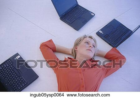 Picture - High angle view of a young woman lying on the floor with open laptops. Fotosearch