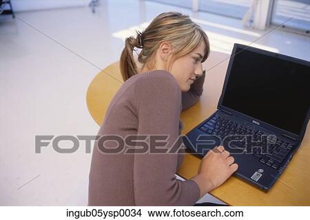 High angle view of a young woman sitting with her hand on a laptop View Large Photo Image Picture - High angle view of a young woman sitting with her hand on a laptop. Fotosearch