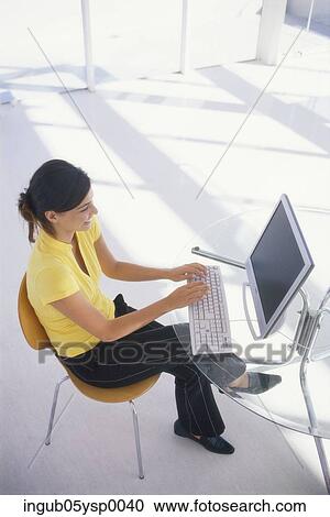Stock Image - High angle view of a young woman working on a computer. Fotosearch