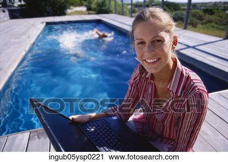 High angle view of a young woman holding a laptop at a poolside View Large Photo Image Stock Image - High angle view of a young woman holding a laptop at a poolside. Fotosearch