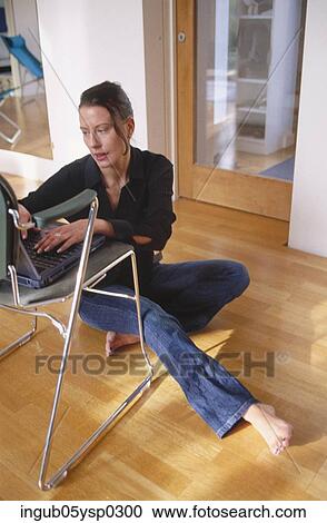High angle view of a young woman sitting on the floor and using a laptop View Large Photo Image Stock Image - High angle view of a young woman sitting on the floor and using a laptop. Fotosearch
