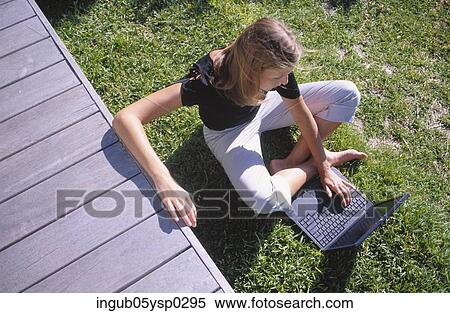 High angle view of a young woman sitting in a lawn with a laptop View Large Photo Image Stock Photography - High angle view of a young woman sitting in a lawn with a laptop. Fotosearch