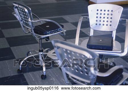 Stock Photograph - High angle view of laptops kept on chairs. Fotosearch