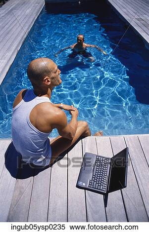 High angle view of two young men sitting at a poolside View Large Photo Image Stock Photography - High angle view of two young men sitting at a poolside. Fotosearch