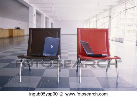 Stock Image - Laptops kept on chairs in an office corridor. Fotosearch