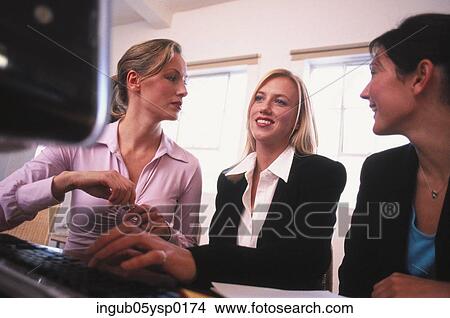 Picture - Low angle view of a three young women talking in an office. Fotosearch