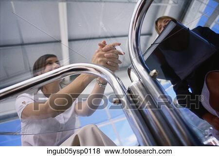 Stock Photo - Low angle view of a two women sitting at a table. Fotosearch