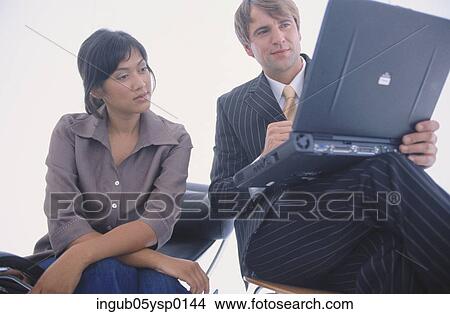 Low angle view of a young man and a young woman working on a laptop View Large Photo Image Picture - Low angle view of a young man and a young woman working on a laptop. Fotosearch
