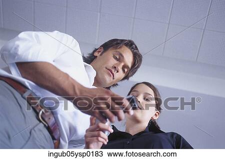 Low angle view of a young man and a young woman looking at a mobile phone View Large Photo Image Stock Image - Low angle view of a young man and a young woman looking at a mobile phone. Fotosearch