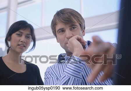 Low angle view of a young woman and a young man viewing a computer screen View Large Photo Image Stock Image - Low angle view of a young woman and a young man viewing a computer screen. Fotosearch