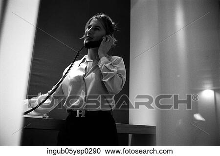 Stock Image - Low angle view of a young woman using a telephone. Fotosearch
