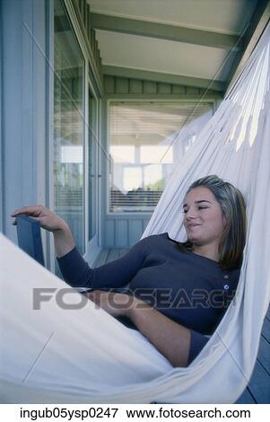 Stock Photo - Low angle view of a young woman with lying in a hammock with a laptop. Fotosearch