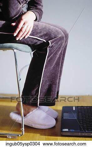 Picture - Low-section view of a woman sitting on a chair. Fotosearch