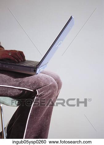 Stock Image - Low-section view of a woman working on a laptop. Fotosearch