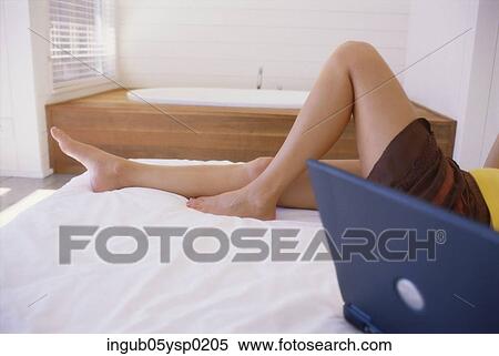 Low-section view of a young woman lying on a bed View Large Photo Image Stock Photography - Low-section view of a young woman lying on a bed. Fotosearch