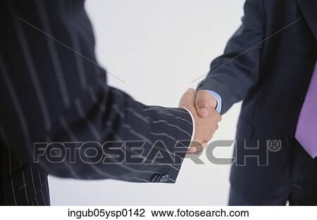 Stock Image - Midsection view of two businessmen shaking hands. Fotosearch