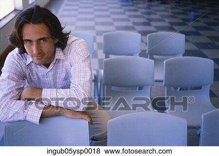 Portrait of a young man sitting on a chair View Large Photo Image Stock Photo - Portrait of a young man sitting on a chair. Fotosearch