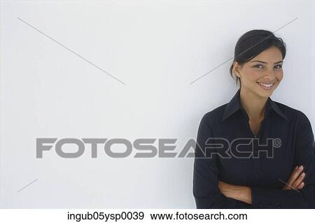 Stock Photo - Portrait of a young woman standing with her arms folded. Fotosearch