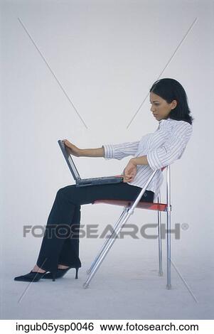 Side profile of a Businesswoman sitting on a chair with a laptop View Large Photo Image Stock Photograph - Side profile of a Businesswoman sitting on a chair with a laptop. Fotosearch