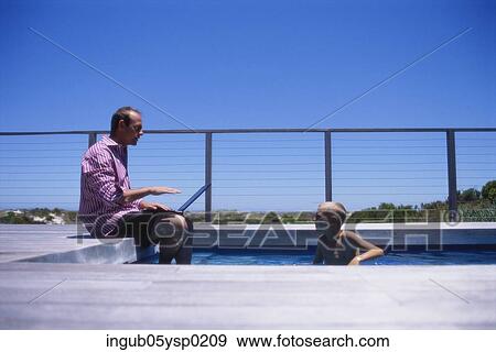 Stock Photo - Side profile of a father and child at a swimming pool. Fotosearch