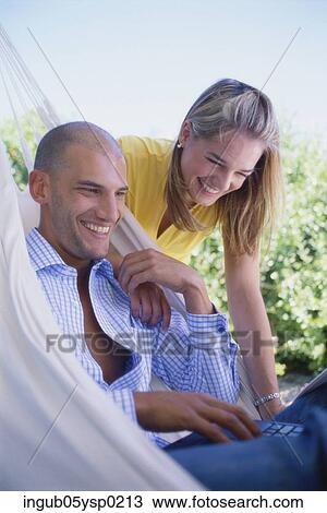Side profile of a young couple looking at a laptop and smiling View Large Photo Image Stock Image - Side profile of a young couple looking at a laptop and smiling. Fotosearch