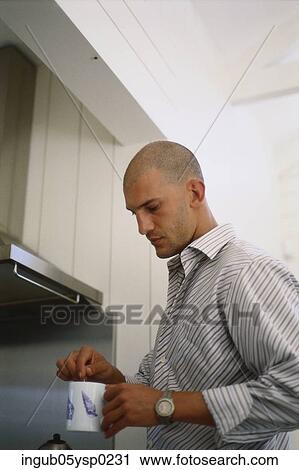 Side profile of a young man stirring a cup of coffee View Large Photo Image Stock Image - Side profile of a young man stirring a cup of coffee. Fotosearch