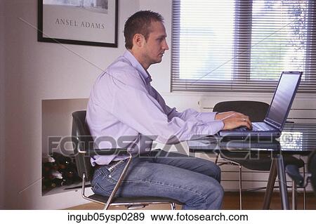 Stock Photo - Side profile of a young man working on a laptop. Fotosearch