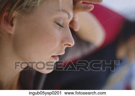 Side profile of a young woman holding her forehead View Large Photo Image Stock Image - Side profile of a young woman holding her forehead. Fotosearch