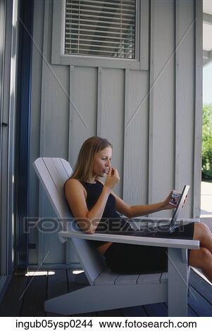 Side profile of a young woman sitting in a chair with a laptop View Large Photo Image Picture - Side profile of a young woman sitting in a chair with a laptop. Fotosearch