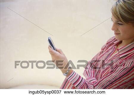 Stock Photo - Side profile of a young woman using a mobile phone. Fotosearch