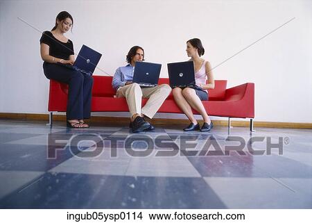 Two young women and a young man working on laptops View Large Photo Image Picture - Two young women and a young man working on laptops. Fotosearch