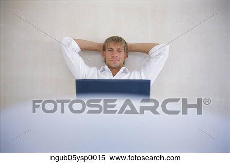 Young businessman sitting on a chair with a laptop View Large Photo Image Stock Photography - Young businessman sitting on a chair with a laptop. Fotosearch