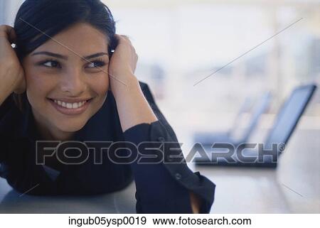 Stock Photo - Young businesswoman lying on her stomach and smiling. Fotosearch