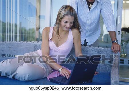 Young couple looking at a laptop View Large Photo Image Stock Photography - Young couple looking at a laptop. Fotosearch