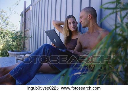 Stock Photography - Young couple sitting on the floor with a laptop. Fotosearch